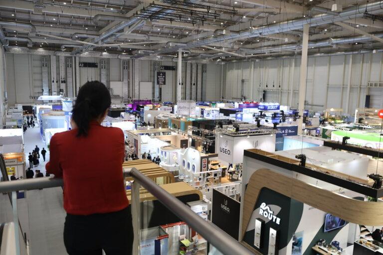 Woman stands on a raised platform looking out at exhibition stands at WTCE 2024